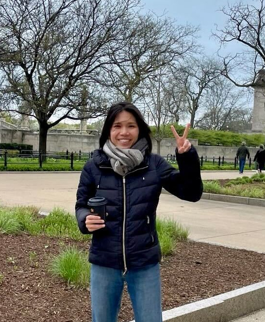 A picture of Trang Nguyen smiling and making a peace sign with her fingers.